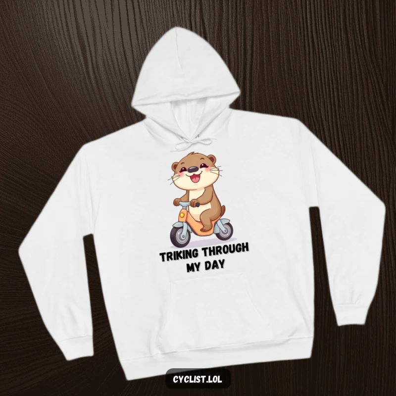 Funny hoodie depicting a curious otter joyfully riding a miniature tricycle, perfect for cozy and humorous wear.